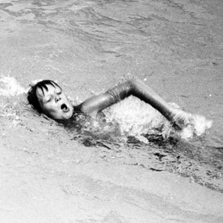 Person swimming underwater in pool.