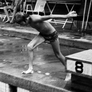 Swimmers warming up at poolside blocks.
