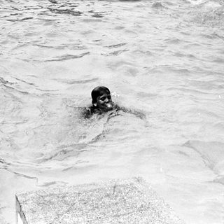 Person swimming in turbulent water near shore.