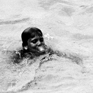Person swimming in turbulent water near shore.