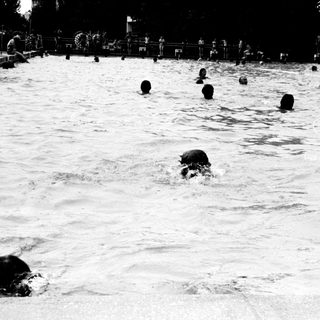 People swimming in a crowded outdoor pool.