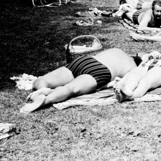 People relaxing on beach towels at nighttime poolside.