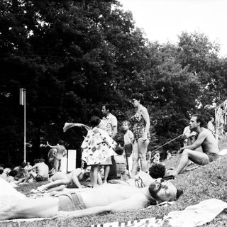 People relaxing and sunbathing outdoors in park.
