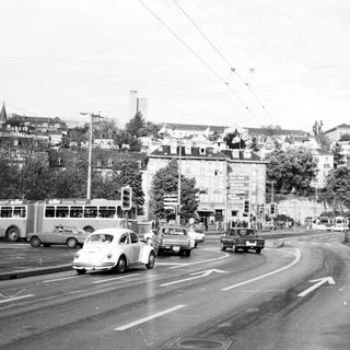 Busy urban street intersection with vintage cars.