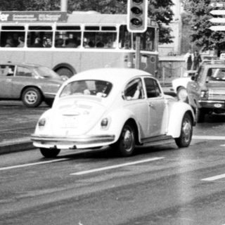 Busy urban street intersection with vintage cars.