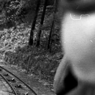 Narrow-gauge train traveling through forested mountain track.