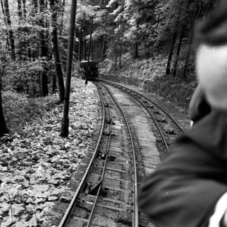 Narrow-gauge train traveling through forested mountain track.