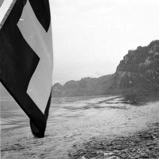 Boat sailing near rocky cliffside in misty water.