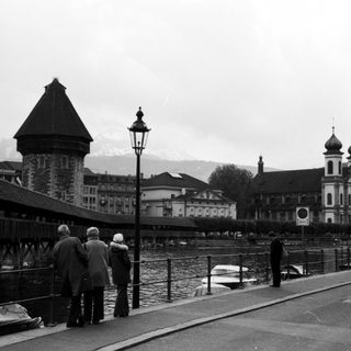 Scenic Swiss bridge with historic buildings and mountains.