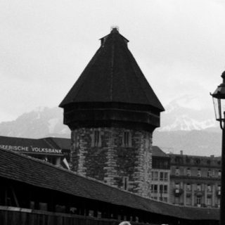 Scenic Swiss bridge with historic buildings and mountains.