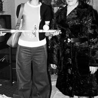 Two women posing with a ski pole indoors near a Christmas tree.