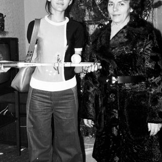 Two women posing with a ski pole indoors near a Christmas tree.