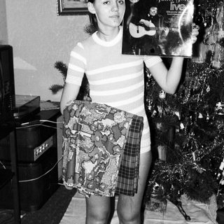 Young woman holding a record album near a Christmas tree.