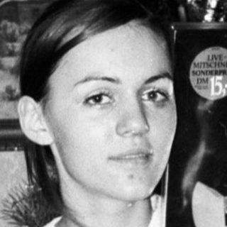 Young woman holding a record album near a Christmas tree.