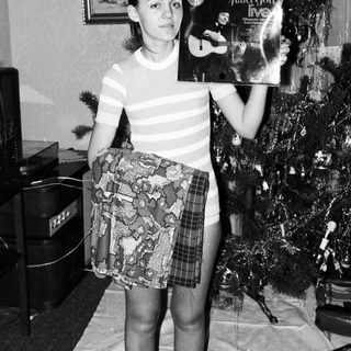 Young woman holding a record album near a Christmas tree.