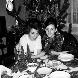 Two women seated at festively set Christmas table.