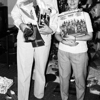 Two people holding awards and magazines indoors.