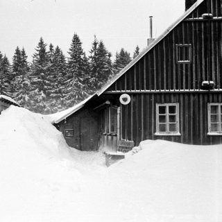 Snow-covered mountain lodge with steep roof.
