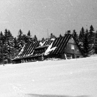 Snow-covered mountain resort with buildings and forested hillside.
