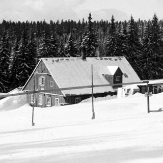Snow-covered mountain lodge in forested area.