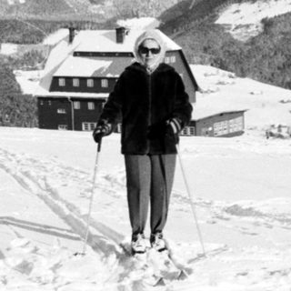 Two people cross-country skiing in snowy mountainous landscape.