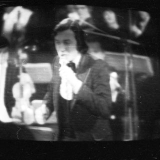 Vintage black-and-white photo of a woman singing into microphone.