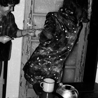 Two women playing a playful game near a stove.