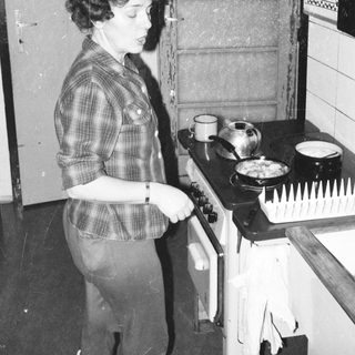 Woman cooking on vintage gas stove.