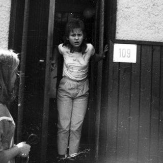 Two children at apartment door, one peeking out.