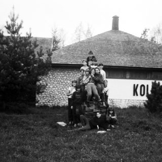 Group of people posing on luggage in front of a building.