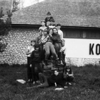 Group of people posing on luggage in front of a building.