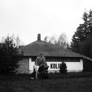 Group posing outside a building labeled "Kolibri" in outdoor setting.