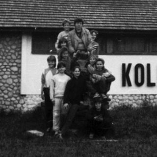 Group posing outside a building labeled "Kolibri" in outdoor setting.