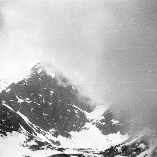 Snow-covered mountain peak shrouded in mist.