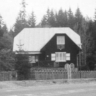 Rural roadside house near forested area.