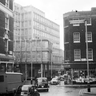 Mid-20th-century urban street scene with vintage cars.