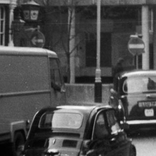 Mid-20th-century urban street scene with vintage cars.