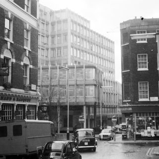 Mid-20th-century urban street scene with vintage cars.
