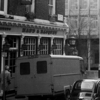 Mid-20th-century urban street scene with vintage cars.