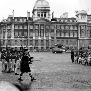 Ceremonial military parade in front of historic building.
