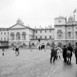 Historic building courtyard with people walking and children playing.