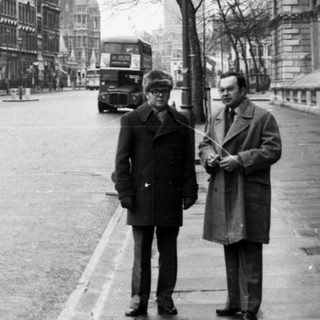 Two men standing near Nelson's Column in London.