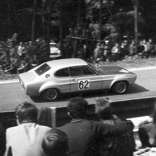 Classic race car numbered 62 on public road.