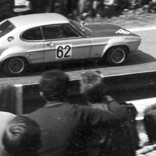 Classic race car numbered 62 on public road.