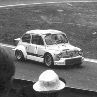 Classic race car driving on curved track.