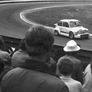 Classic race car driving on curved track.