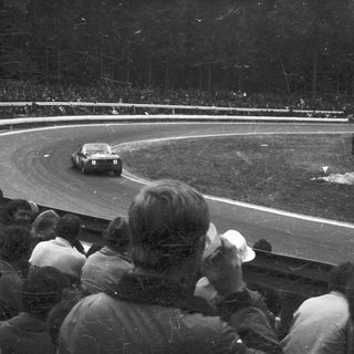 Classic race car on wet track during nighttime event.