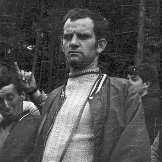 Two men in vintage outdoor attire, one adjusting cap.