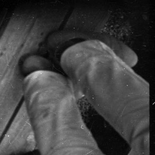 Person stepping on broken glass on ground.