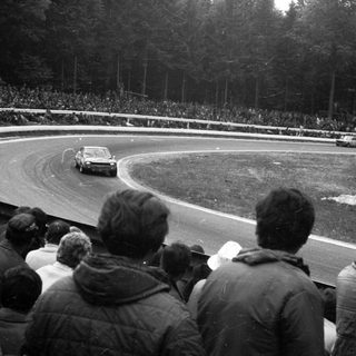 Classic race car on wet track during rally.